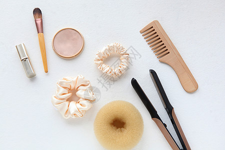 木发刷 直发器和黄色丝绸 Scrunchy 隔离在白色 平躺美发工具和配件 如彩色发带 弹性发带 发带发夹梳子剪刀团体造型沙龙配图片