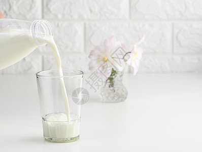 从塑料瓶中倒新鲜牛奶到玻璃杯 白桌的工艺过程瓶子溪流白色早餐养分食物饮料流动产品液体图片