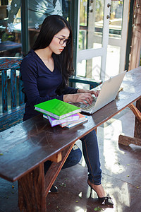在咖啡馆用笔记本电脑工作的妇女桌子商业学习咖啡店酒吧网络学生潮人上网技术图片