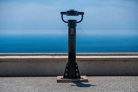 投币式双筒望远镜和蓝色的大海背景 公共全景望远镜观察海景 旅行 放松或孤独的概念图片