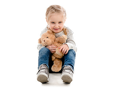 小孩坐着拥抱泰迪 与世隔绝蓝色快乐学生玩具孩子美丽幸福女儿童年微笑图片