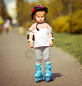 穿着溜冰鞋和头盔的2岁女孩滚筒女性婴儿公园乐趣闲暇享受安全孩子森林图片