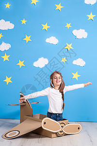 小梦中女孩在工作室玩纸板飞机 蓝天和白云背景的游戏 笑声孩子天空自由航班女孩微笑女性婴儿空军空气图片