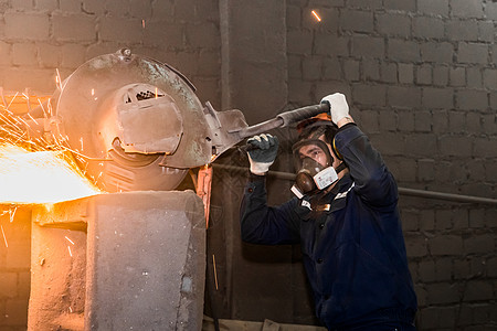一名身戴保护头盔 呼吸器 内服的男性工人管理着重型研磨设备 用于在工厂车间用飞火筒铸铁混凝土浴缸职业工作光盘磨盘金属软垫工具研磨图片