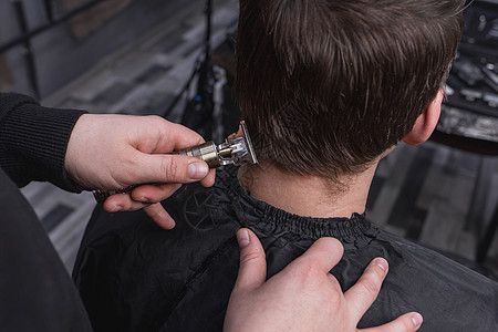 理发师或美发师的手用便携式推剪剪掉了一位留着深色长发的客户的后脑勺 理发理发店男人发型发型师店铺潮人服务造型师成人梳子图片