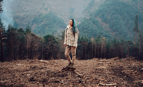 站立在树桩上的旅行者女性森林女孩游客女士场地木头背包探险家旅行图片