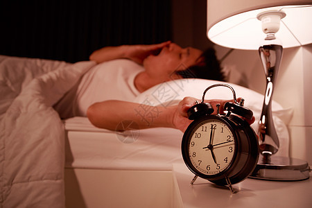 睡着的年轻男子在床上 手伸向清晨的闹钟卧室警报男性睡眠头痛枕头苏醒痛苦时间唤醒图片