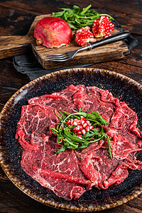 Carpaccio 大理石板牛肉肉 配有花生和石榴种子 木质背景图片