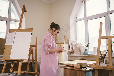 白人女艺术家在明亮的日光工作室里创作一幅画 快乐的艺术家在车间里用油漆和画笔绘制一个艺术项目 爱好 艺术家在工作 创意职业画廊画图片