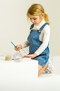可爱的金发女孩坐在她的膝盖上 用笔刷画画学习绘画乐趣班级刷子画笔桌子画家童年幼儿园图片