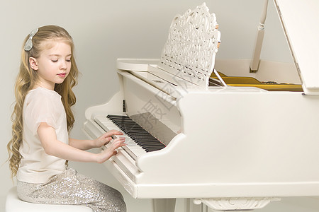 女孩在白色大钢琴上玩家钢琴家孩子女士童年裙子音乐键盘潮人女性图片
