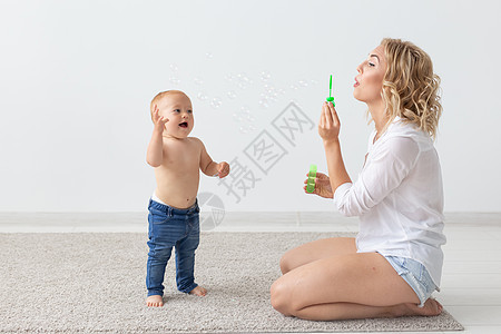 家庭和为人父母的概念     可爱的婴儿在蜜蜂地毯上与母亲玩耍女孩生活成人金字塔母性教育玩具乐趣赤脚喜悦图片