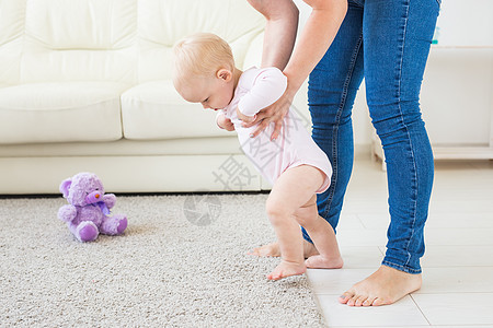 婴儿幼儿开始学习在阳光明媚的白色起居室走步 给孩子穿脚椅子父母晴天窗户男生玩具童年儿子母亲骨科图片