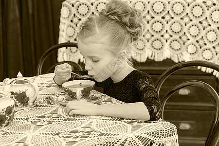 美丽的小女孩在餐桌上喝茶 笑声孩子杯子青年婴儿幸福裙子孩子们童年微笑食物图片
