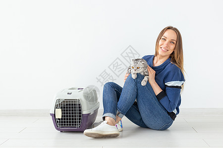 迷人的正派年轻女人手里握着 她美丽的灰色折叠苏格兰猫 坐在地上 在新公寓里 宠物概念婴儿乐趣短发毛皮猫咪血统小猫虎斑晶须动物图片