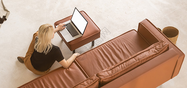 中年妇女的肖像使用她的空白屏幕笔记本电脑 坐在家里沙发上背对背头发银行业妻子房间窗户女性工作女孩展示商业图片