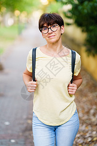 美丽的中年女子在街上走过白色微笑妇女女性公园样机女孩服装花园眼镜图片