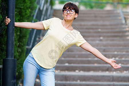 在城市公园里 快乐的中年女人闲暇眼镜白色花园成人服装公园样机幸福女性图片