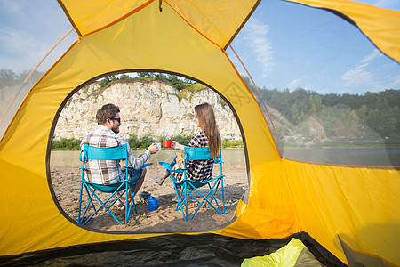 人民 旅游和自然概念     坐在黄色帐篷附近的可爱情侣女性娱乐快乐假期微笑压痛圆圈男人爬坡拥抱图片