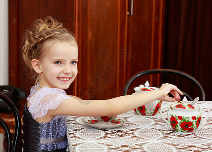 可爱的小女孩在旧桌边喝茶童年婴儿女性食物坡度派对孩子们孩子幸福杯子图片
