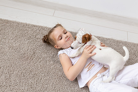 宠物 童年和动物概念与小狗杰克罗素泰里尔躺在地上的小女孩肖像灰色犬类幸福白色猎犬友谊衬衫黑发地面工作室图片