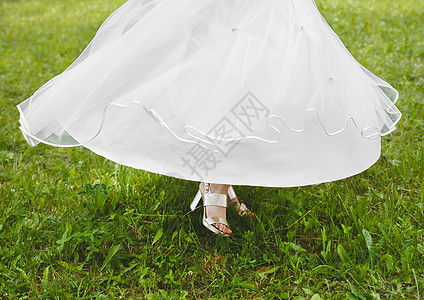 新娘的白色婚纱在公园绿草地上摇晃图片