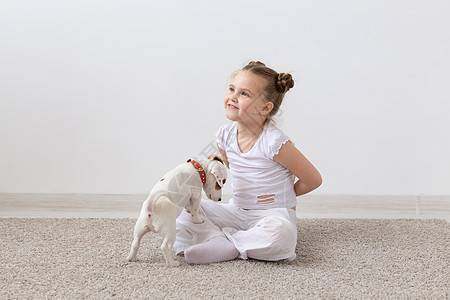 童年 宠物和狗的概念  小狗和穿白衬衫的小女孩玩得开心动物幸福微笑犬类猎犬工作室地面女孩乐趣黑发图片