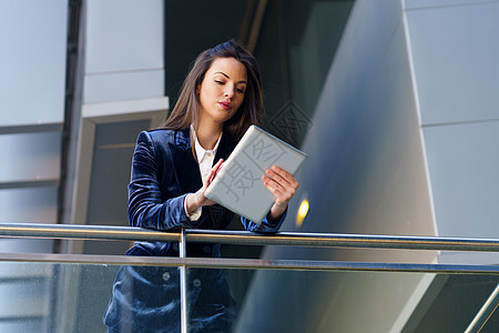 女商务人士穿着蓝色西装 在办公楼使用数字平板电脑管理人员街道套装办公室商业女性工人城市技术企业家图片