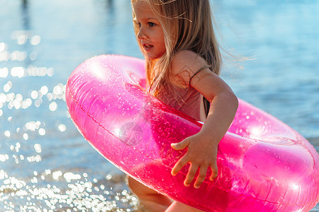 有粉红色充气圆圈在海中洗澡的小女孩棕褐色女孩童年游泳海滩喜悦海岸晴天闲暇海洋图片