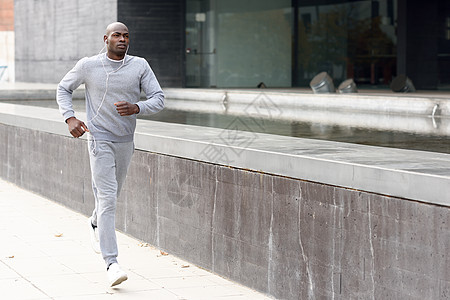 在城市背景下奔跑的有吸引力的黑人男子福利肌肉跑步慢跑者耳机运动员黑色运动锻炼身体图片