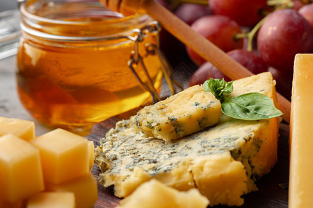 灰色表面配有葡萄和蜂蜜的奶酪木板小吃砧板产品食物桌子背景图片
