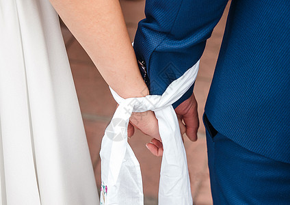 新娘和新郎绑在一起的双手紧紧地靠在一起女孩领带订婚已婚婚姻裙子夫妻男人女性传统图片