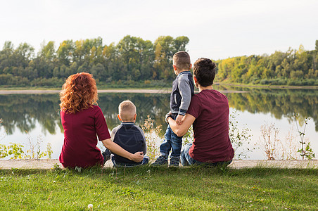 童年和自然概念     家庭 小儿子坐在绿草上男生衬衫孩子们天空母亲公园头发卷曲太阳父母图片