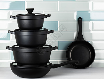 针对蓝色瓷砖墙的新黑餐具黑色烹饪厨房柜台厨具平底锅炊具图片
