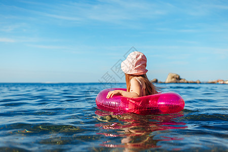 穿粉红巴拿马式的小女孩 在海中游泳 环绕着圆圈闲暇海岸喜悦女孩棕褐色晴天假期享受粉色乐趣图片