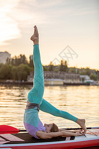 运动型女性在桨板上做瑜伽 在垫板上做瑜伽 锻炼灵活性和伸展肌肉女孩身体意识海滩太阳讲师海洋成人冲浪板冥想图片