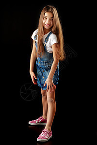 穿戴尼姆服装的小女孩 黑人背景乐趣工作服童年头发女孩工作室衣服粉红色青春期喜悦图片