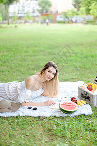 年轻美女在读书 躺在水果和帽子边的草丛上 深藏不露的草地上图片