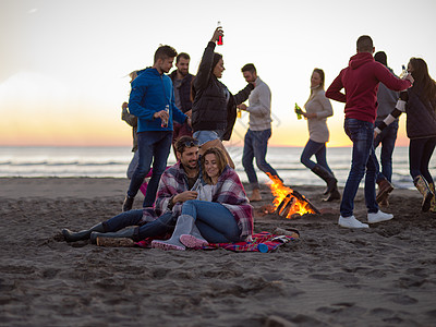 在海滩日落时和朋友共度欢乐的情侣休闲活动男人沙滩潮人夫妻衣服火焰旅行朋友们图片