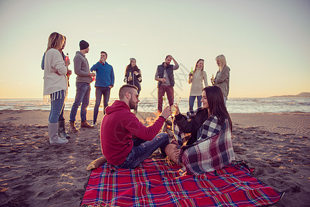 在海滩日落时和朋友共度欢乐的情侣友谊享受派对快乐场景女性假期篝火幸福城市图片