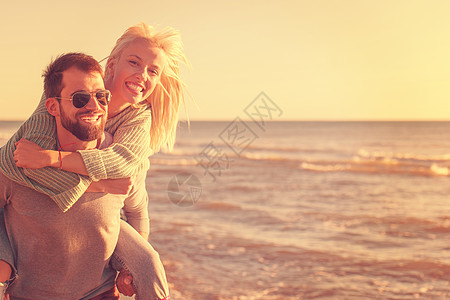 秋天在海滩玩情的情侣阳光背光快乐乐趣潮人海洋骑术女性女朋友男人图片