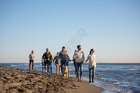 秋天在海滩上奔跑的一群朋友乐趣年轻人海岸鹅卵石帽子跑步友谊情侣朋友们假期图片