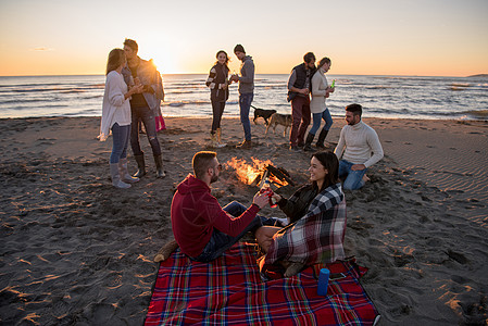 在海滩日落时和朋友共度欢乐的情侣啤酒女性城市享受旅行场景活动火焰营火休闲图片