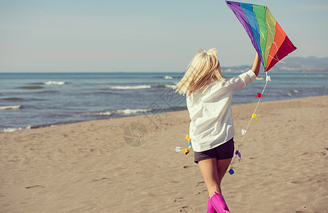 秋天在海滩玩风筝的年轻女子海洋女孩喜悦自由乐趣天空闲暇衬垫巡航天气图片