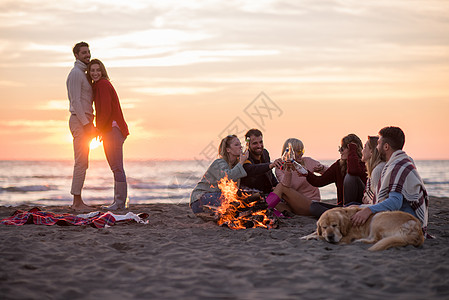 在海滩日落时和朋友共度欢乐的情侣动作幸福朋友们啤酒乐趣假期营火城市潮人快乐图片