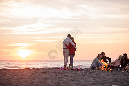 在海滩日落时和朋友共度欢乐的情侣活动篝火夫妻旅行女性假期幸福友谊衣服派对图片