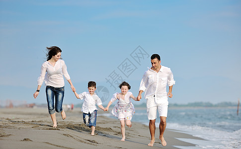 快乐的年轻家庭在海滩上玩得开心女孩女性女士母亲孩子假期父亲儿子男人海洋图片