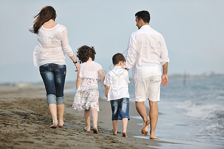 快乐的年轻家庭在海滩上玩得开心母亲成人女孩海洋儿子微笑爸爸男人女儿父亲图片