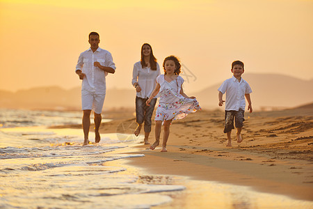 快乐的年轻家庭 在日落时在海滩上玩得开心微笑跑步童年海洋女儿天空太阳女孩儿子女性图片