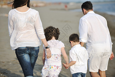 快乐的年轻家庭在海滩上玩得开心爸爸天空女士儿子后代成人孩子女孩旅行男人图片